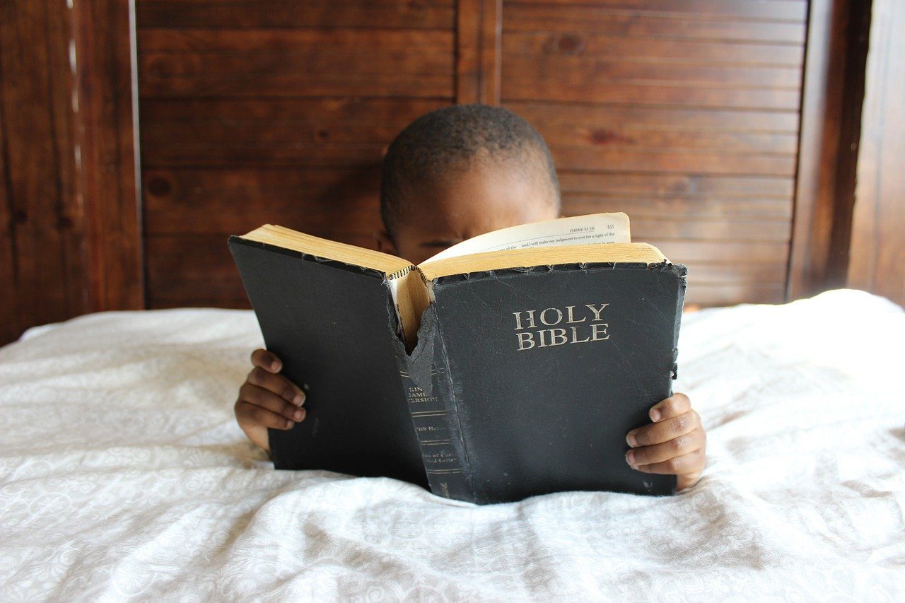 A child reading the bible on his bed