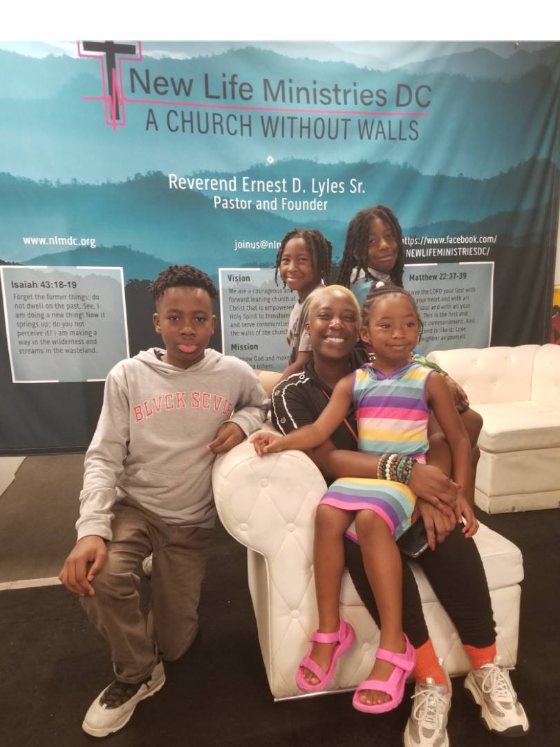 Family sitting together on a couch with a church banner in the background.