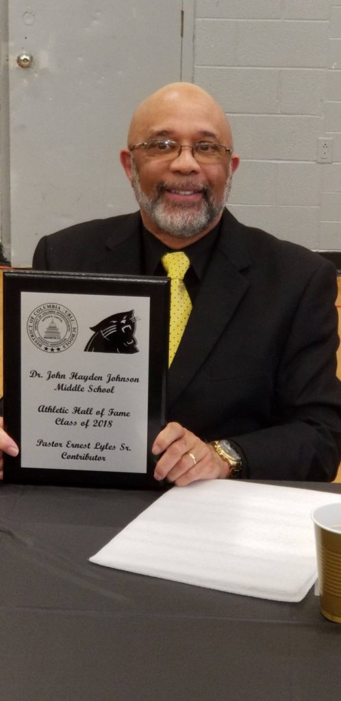 A man holding up a plaque with the words " dr. John hampton jefferson middle school " on it
