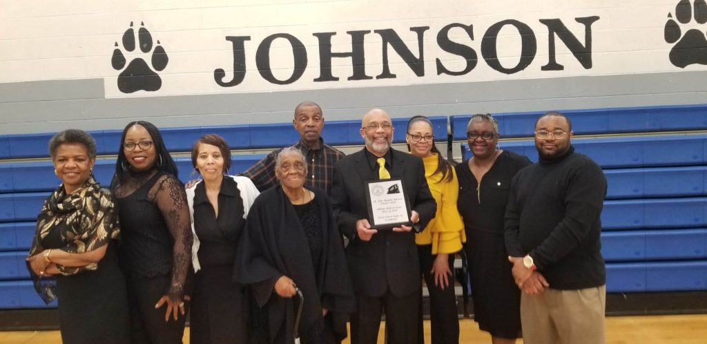 A group of people standing in front of a johnson sign.