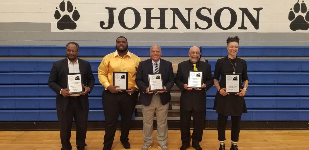 Five men are holding their awards in front of a johnson sign.