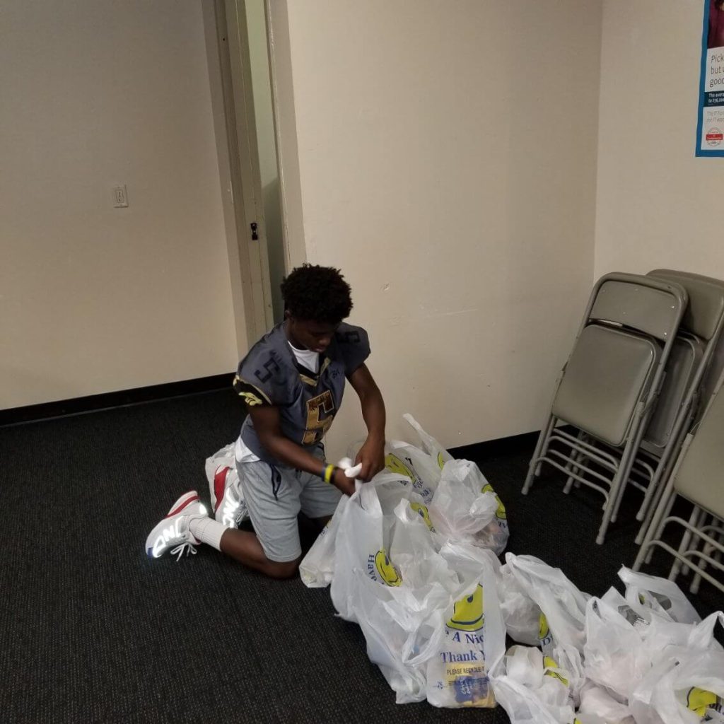 A boy is sitting on the floor and sorting bags of food.