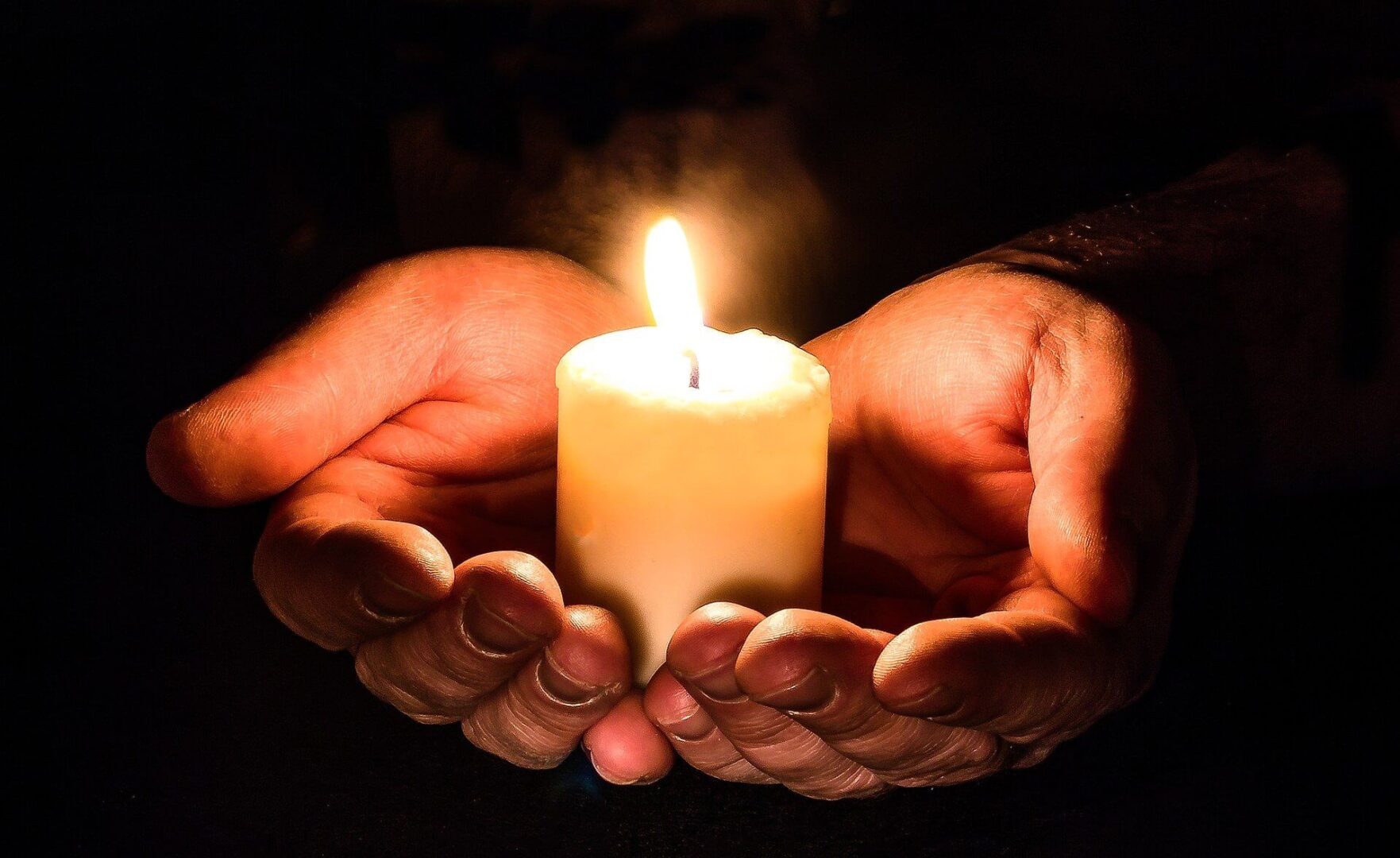 A person holding a candle in their hands.