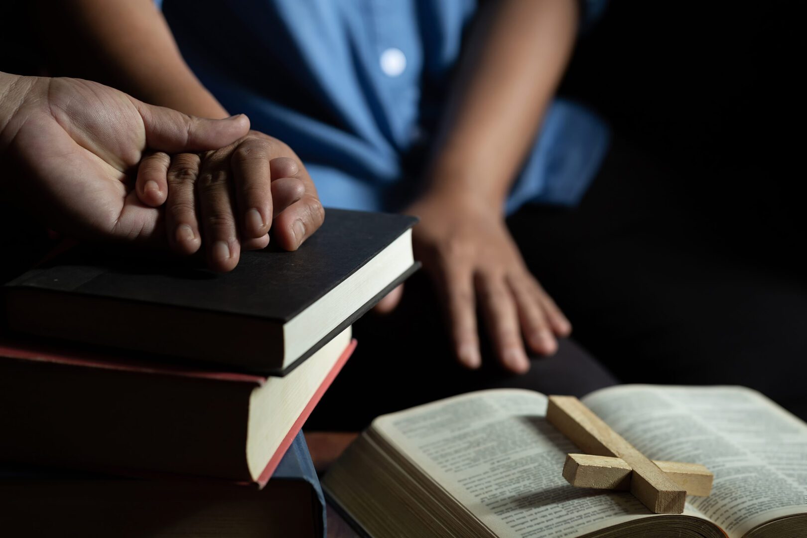 Two people are reading a book and holding hands.