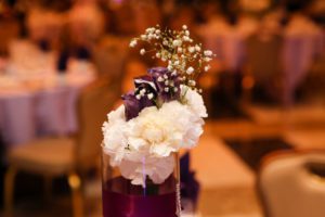 A purple vase with flowers on top of it.