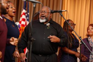 A man with a beard and glasses singing