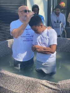 A man performing a baptism on a young individual in a baptismal pool