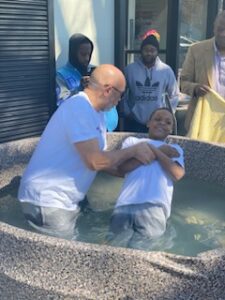 Adult assisting a child in a baptismal ceremony.